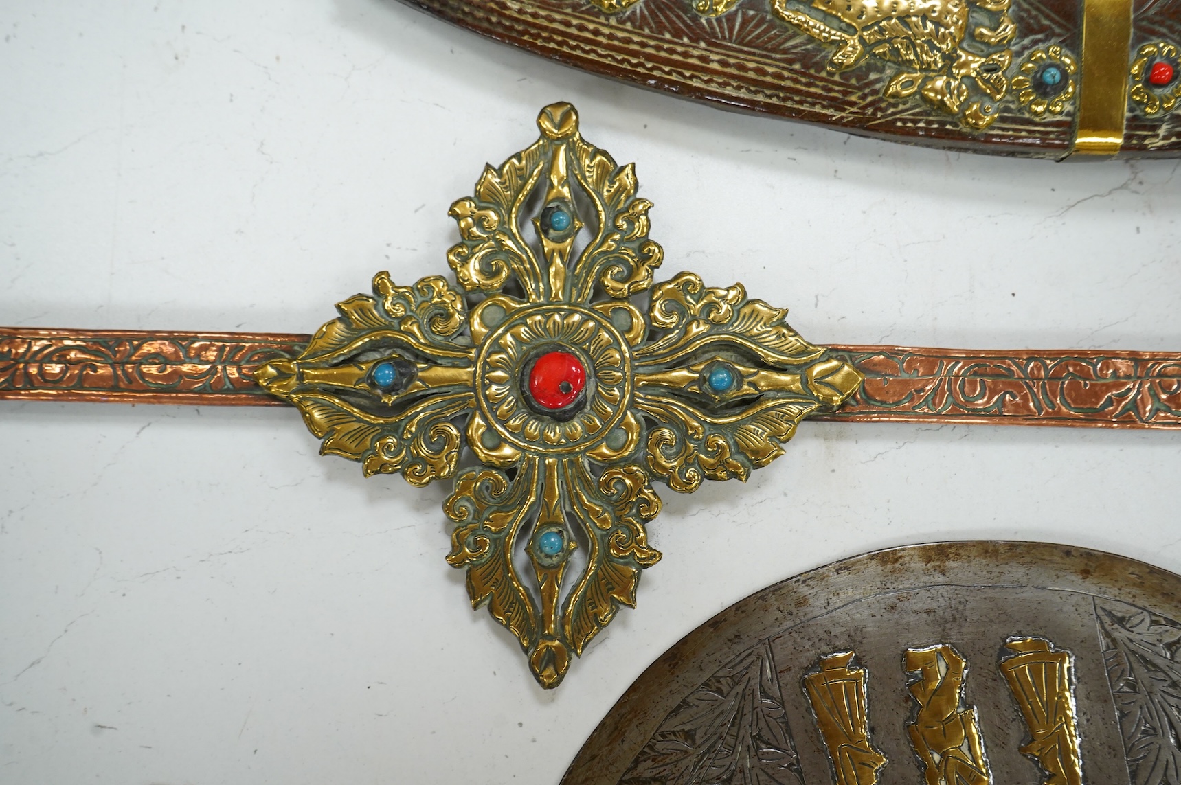 A decorative Indian axe, the large head inlaid with brass Hindu figures, together with a brass mounted North Indian kukri, another similar knife with bone handle, and a large shovel-shaped copper and brass item possibly